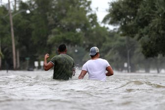 "Erste Auswirkungen von "Barry": Personen waten in Mandeville (US-Staat Louisiana) durch eine überschwemmte Straße.