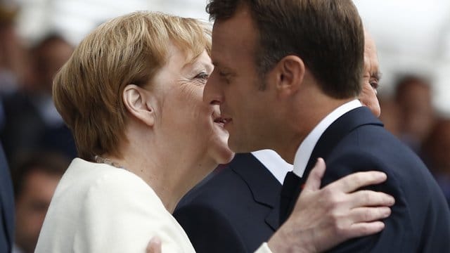 Frankreichs Präsident Emmanuel Macron begrüßt Angela Merkel während der großen Militärparade auf der Prachtstraße Champs-Élysées. Frankreichs Präsident Emmanuel Macron begrüßt Angela Merkel während der großen Militärparade auf der Prachtstraße Champs-Élysées.