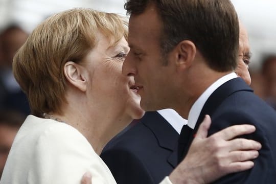 Frankreichs Präsident Emmanuel Macron begrüßt Angela Merkel während der großen Militärparade auf der Prachtstraße Champs-Élysées.