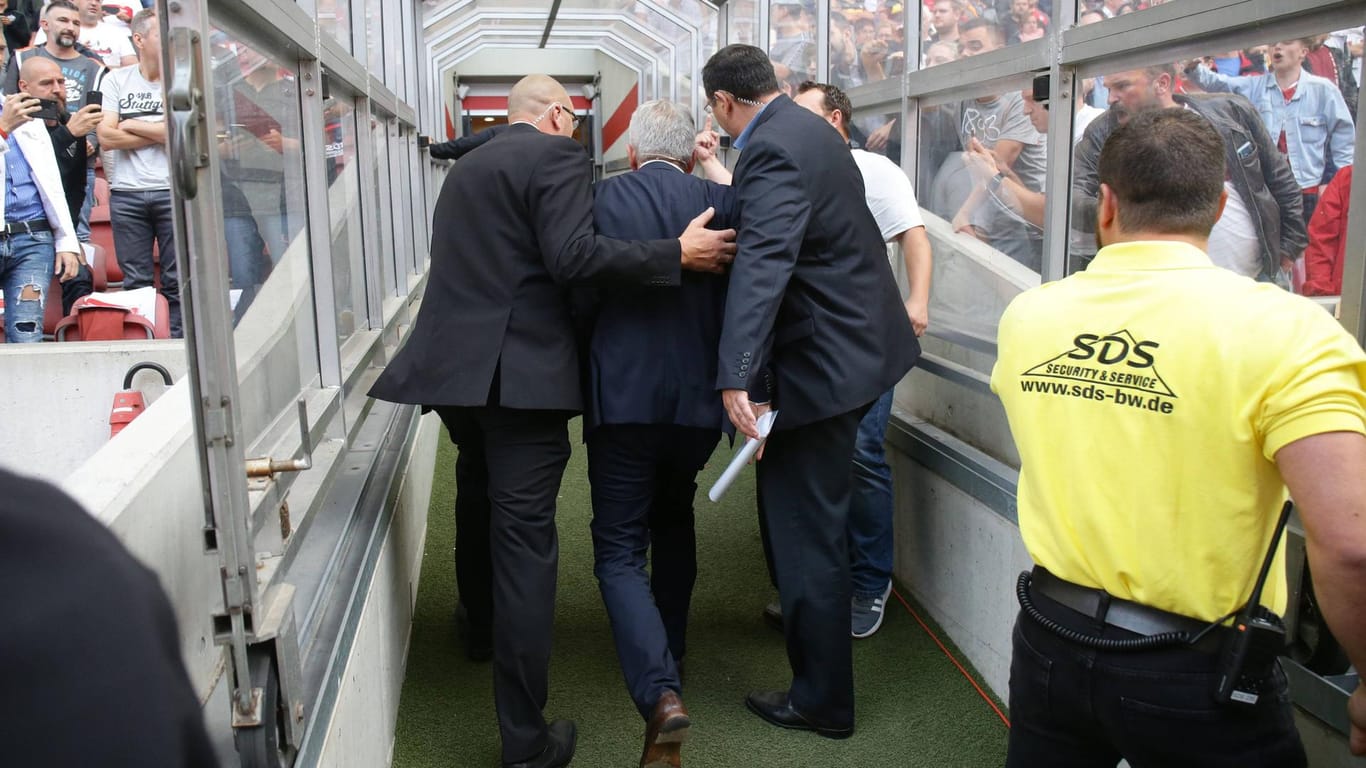 VfB-Präsident Wolfgang Dietrich wird von Leibwächtern aus dem Stadion gebracht, die Fans links und rechts des Spielertunnels filmen und pöbeln.