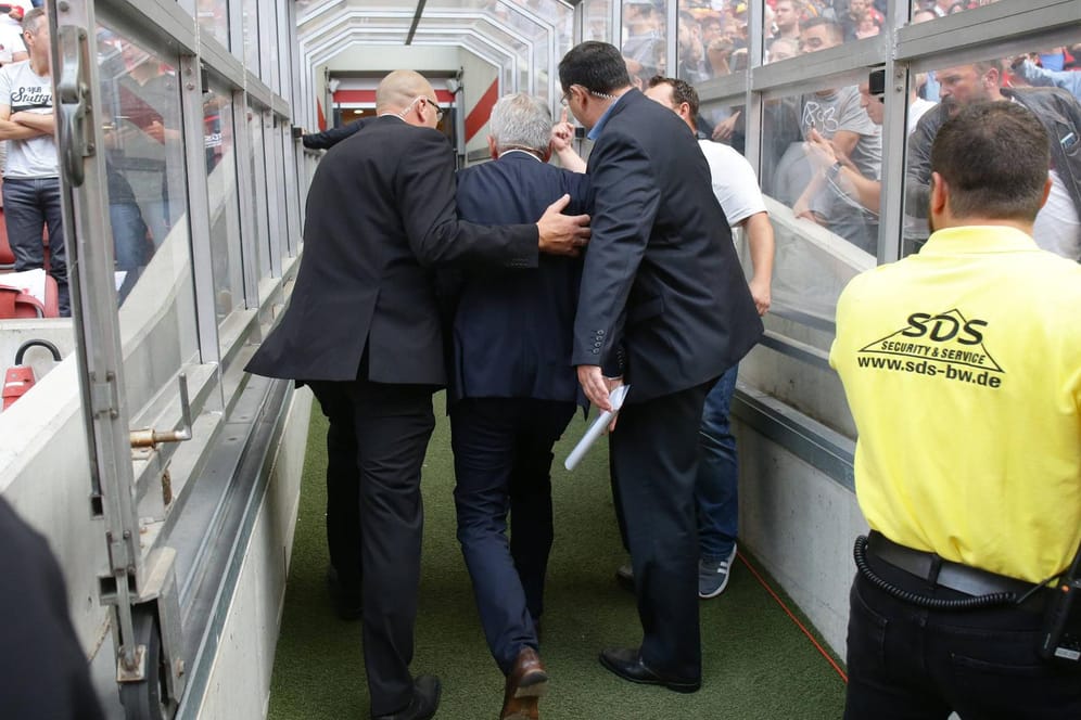 VfB-Präsident Wolfgang Dietrich wird von Leibwächtern aus dem Stadion gebracht, die Fans links und rechts des Spielertunnels filmen und pöbeln.