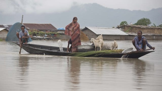 Dorfbewohner fahren mit einem Boot entlang des Flusses Brahmaputra. Dorfbewohner fahren mit einem Boot entlang des Flusses Brahmaputra.