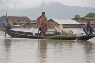 Dorfbewohner fahren mit einem Boot entlang des Flusses Brahmaputra.