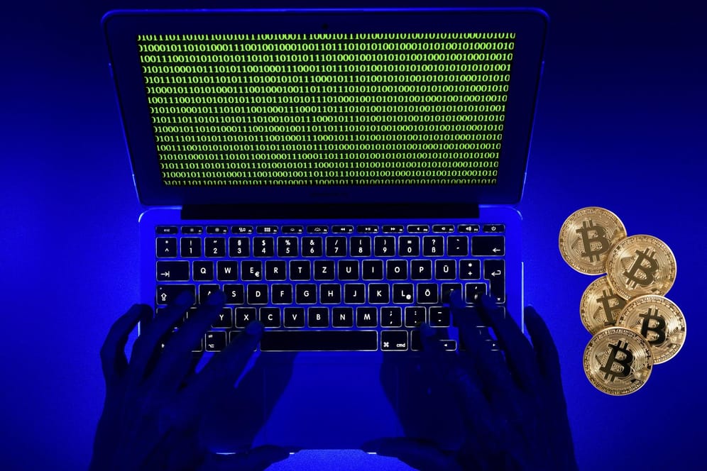 Das Symbolbild zeigt einen Laptop mit Binärcode und Bitcoin-Münzen: Internetkriminelle setzen verstärkt auf den Einsatz von sogenannten Krypto-Minern.