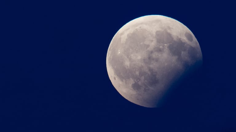 Bei einer partiellen Mondfinsternis verdunkelt sich der Mond teilweise, weil er durch den Erdschatten wandert.
