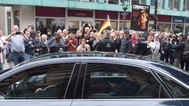 Der Dienstwagen der Bundeskanzlerin fährt an Demonstranten vor dem Albertinum vorbei.