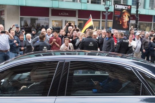 Der Dienstwagen der Bundeskanzlerin fährt an Demonstranten vor dem Albertinum vorbei.