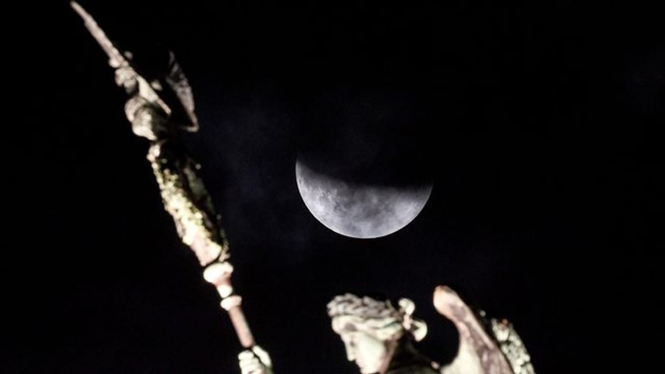 Der Mond ist während einer partiellen Mondfinsternis hinter der Quadriga des Brandenburger Tors zu sehen.