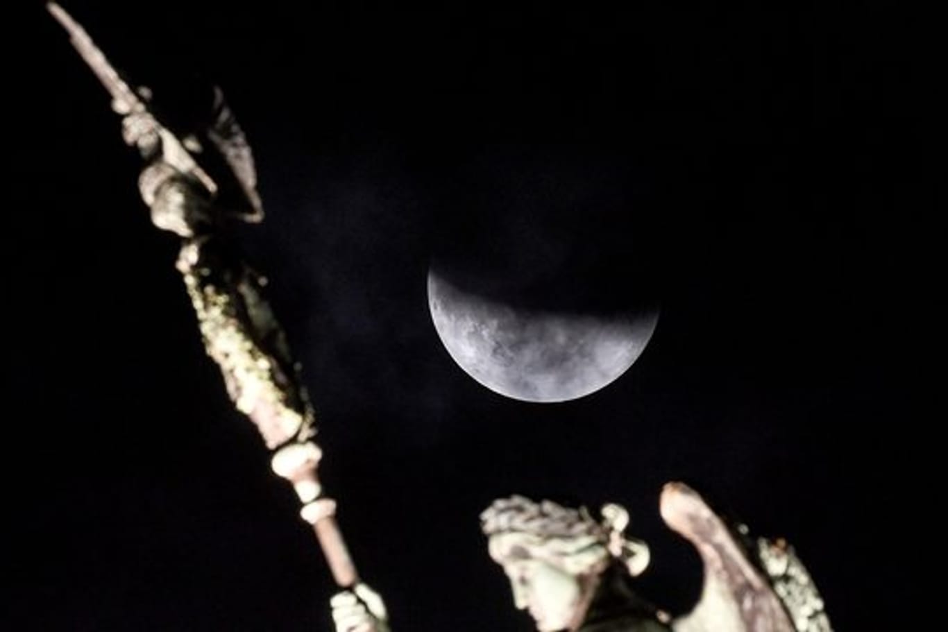 Der Mond ist während einer partiellen Mondfinsternis hinter der Quadriga des Brandenburger Tors zu sehen.