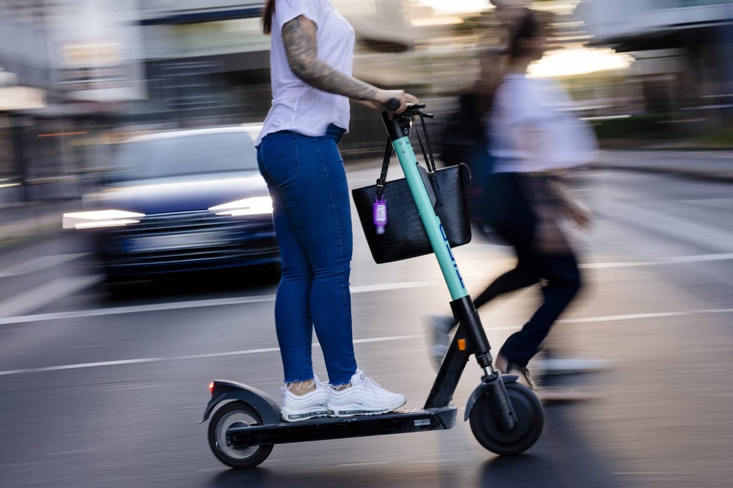 E Scooter Fahrerin in der Kölner Innenstadt: Klappbare E-Tretroller dürfen kostenlos in Bus und Bahn mitgenommen werden.