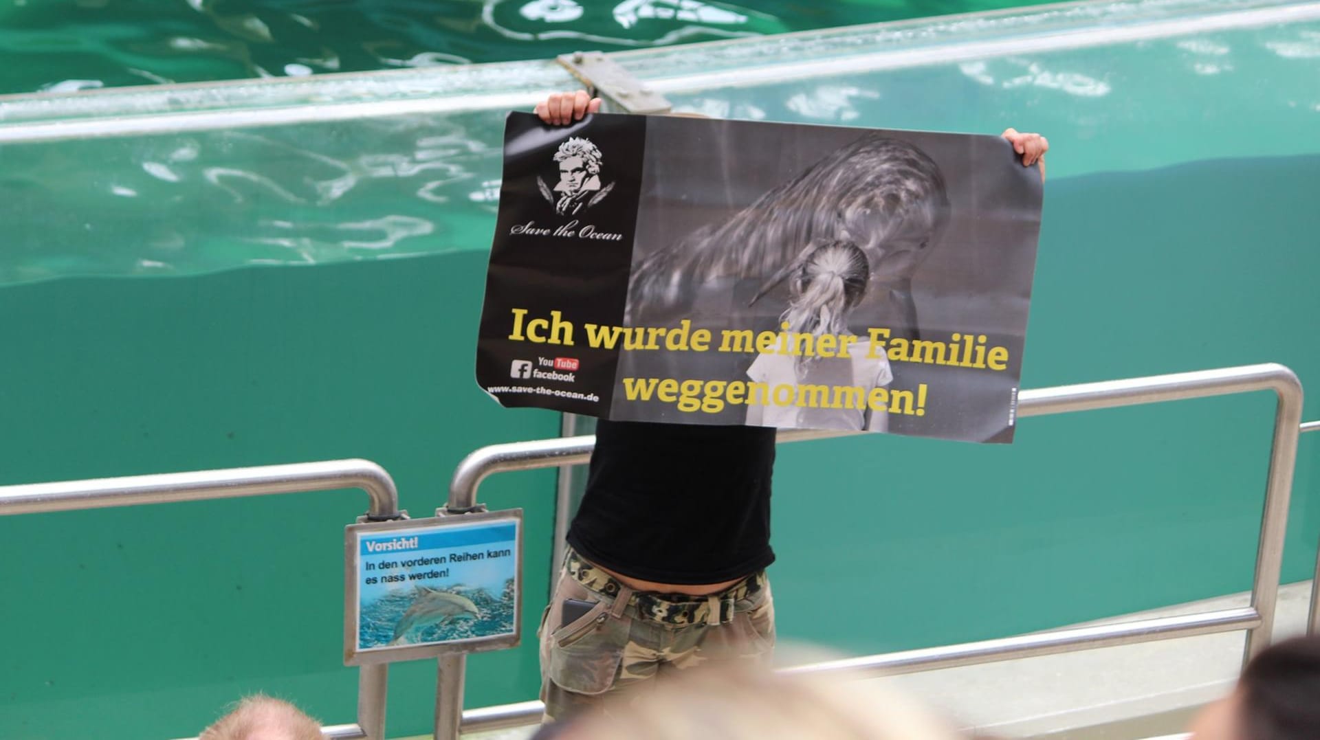 Aktion im Delfinarium: Ein Aktivist hält vor dem Delfinbecken ein Plakat hoch.