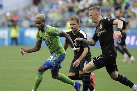 Joevin Jones von den Seaattle Sounders (l) wird von den BVB-Spielern Marius Wolf (r) und Mario Götze attackiert.