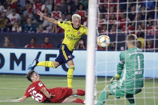 Arsenal-Spieler Mesut Özil (M/oben) kommt gegen Jonas Kehl (l) zum Schuss auf das Tor von Manuel Neuer.