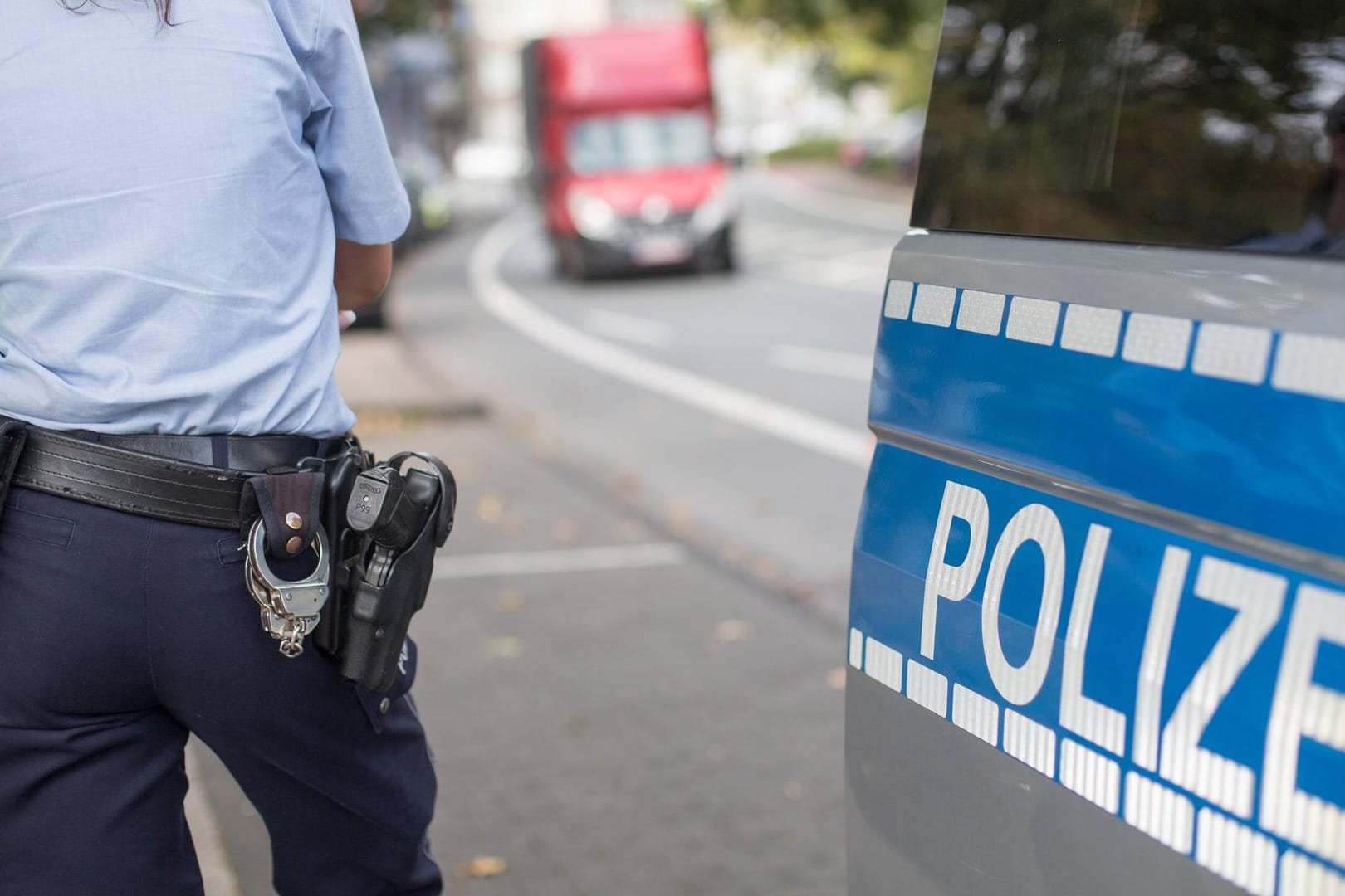 Polizistin neben einem Streifenwagen: Ein Lkw-Fahrer schaute auf sein Handy und fuhr deshalb über Rot. (Symbolbild)