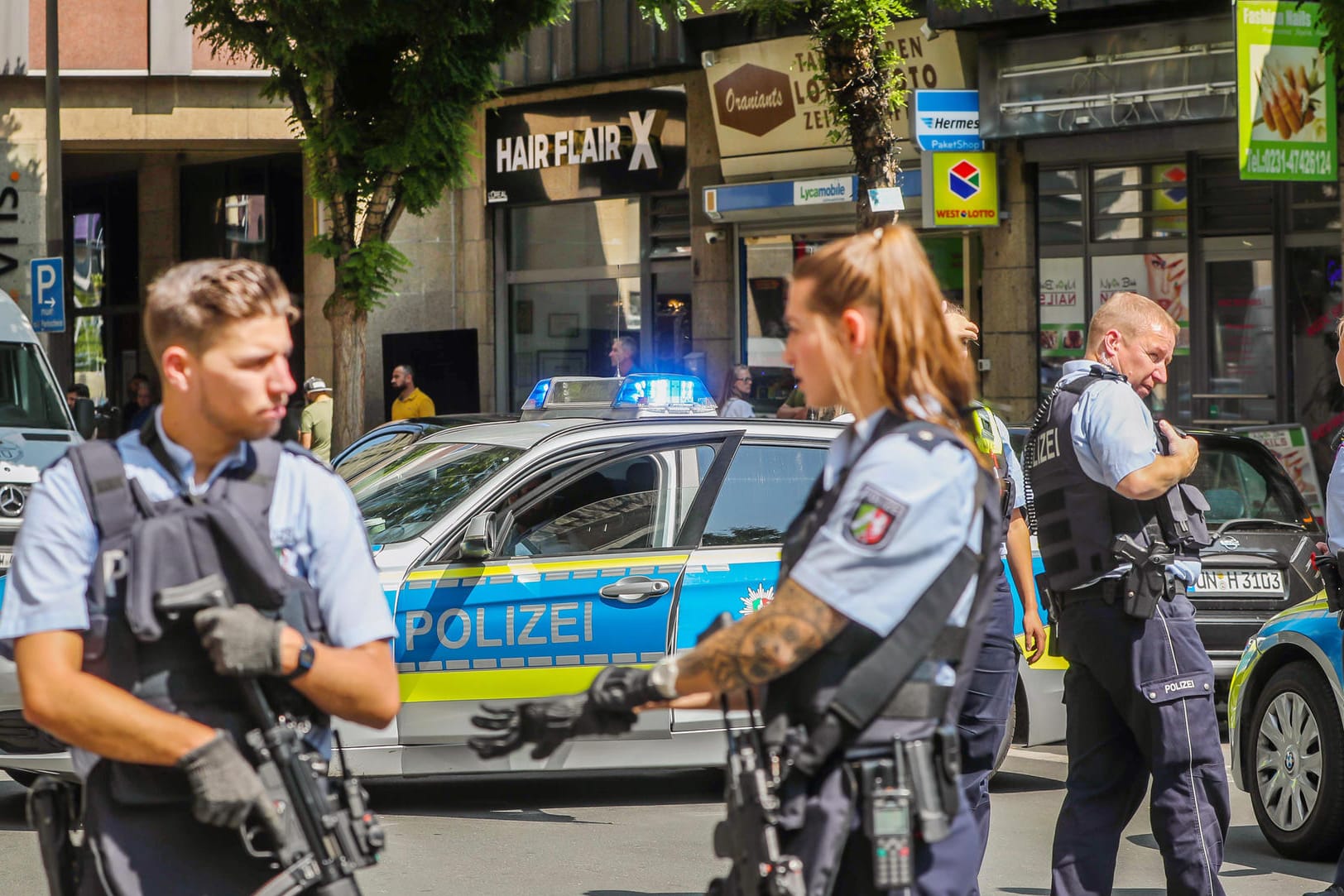 Polizisten stehen in Dortmund vor einem Friseursalon