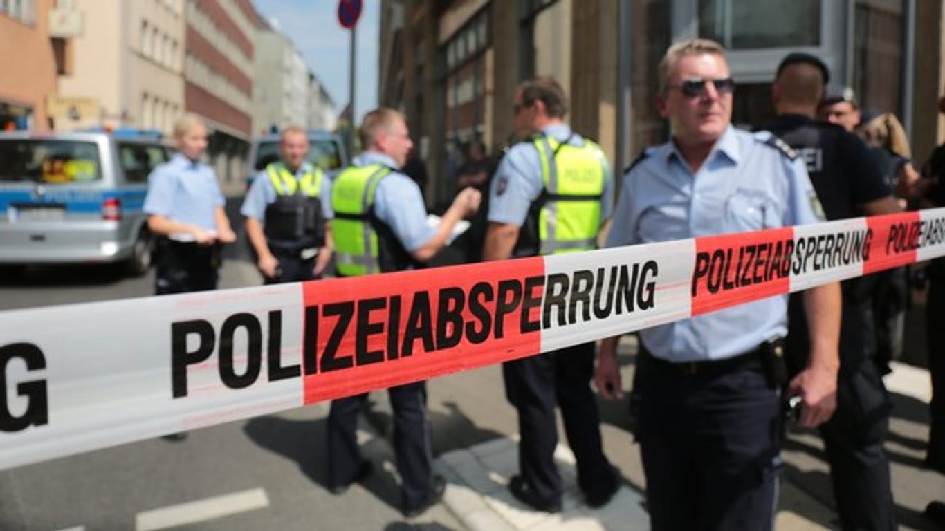 Polizisten stehen vor einem Wohngebäude eines der mutmaßlichen Gefährder in der Kölner Innenstadt hinter einem Absperrband.