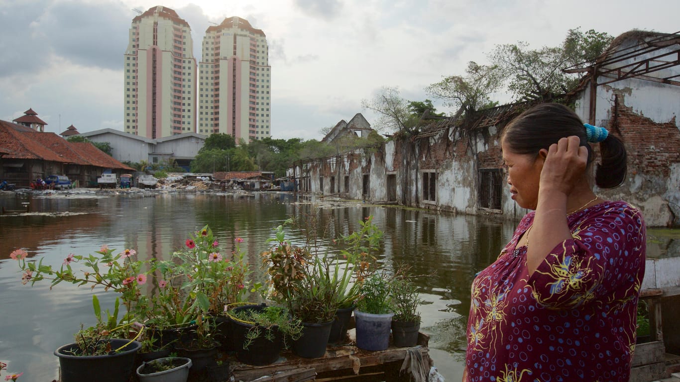 Eine Frau schaut auf eine überflutete Fläche in Jakarta: Die indonesische Hauptstadt, in deren Großraum rund 30 Millionen Mensche leben, droht zu versinken.