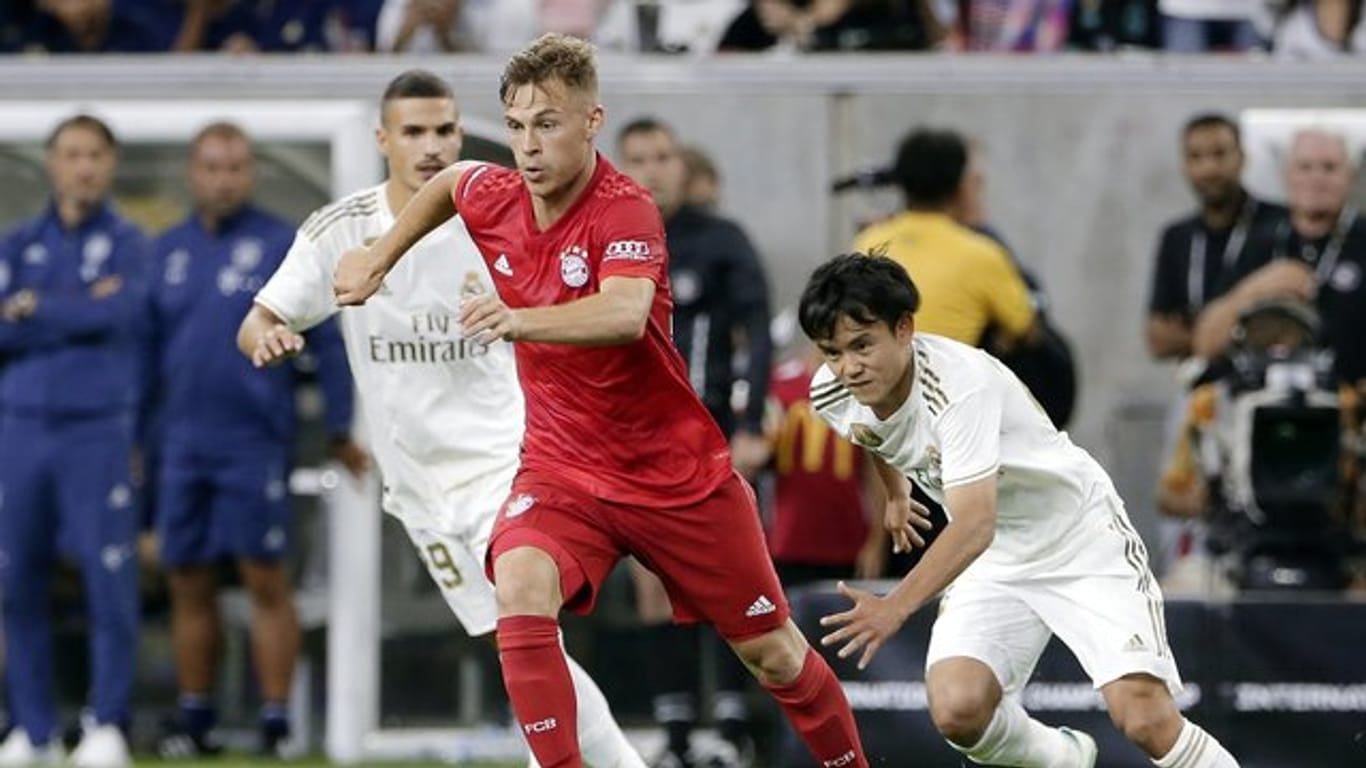 Joshua Kimmich (M) setzt sich am Bell gegen Karim Benzema (l) und Takefusa Kubo von Real Madrid durch.