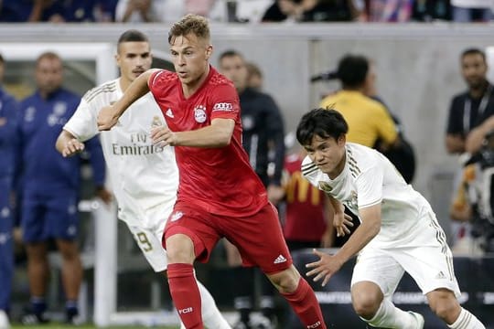 Joshua Kimmich (M) setzt sich am Bell gegen Karim Benzema (l) und Takefusa Kubo von Real Madrid durch.
