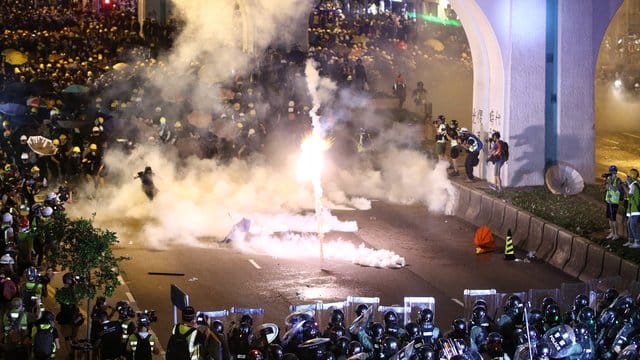 Polizisten feuern bei den Massenprotesten in Hongkong mit Tränengas auf die Demonstranten. Polizisten feuern bei den Massenprotesten in Hongkong mit Tränengas auf die Demonstranten.