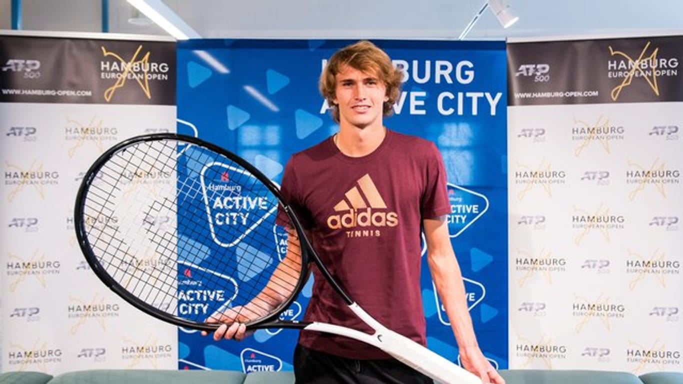Alexander Zverev posiert in Hamburg während einer Pressekonferenz mit einem überdimensionalen Tennisschläger.