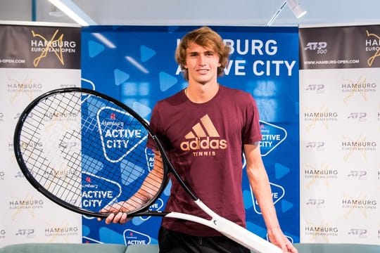 Alexander Zverev posiert in Hamburg während einer Pressekonferenz mit einem überdimensionalen Tennisschläger.