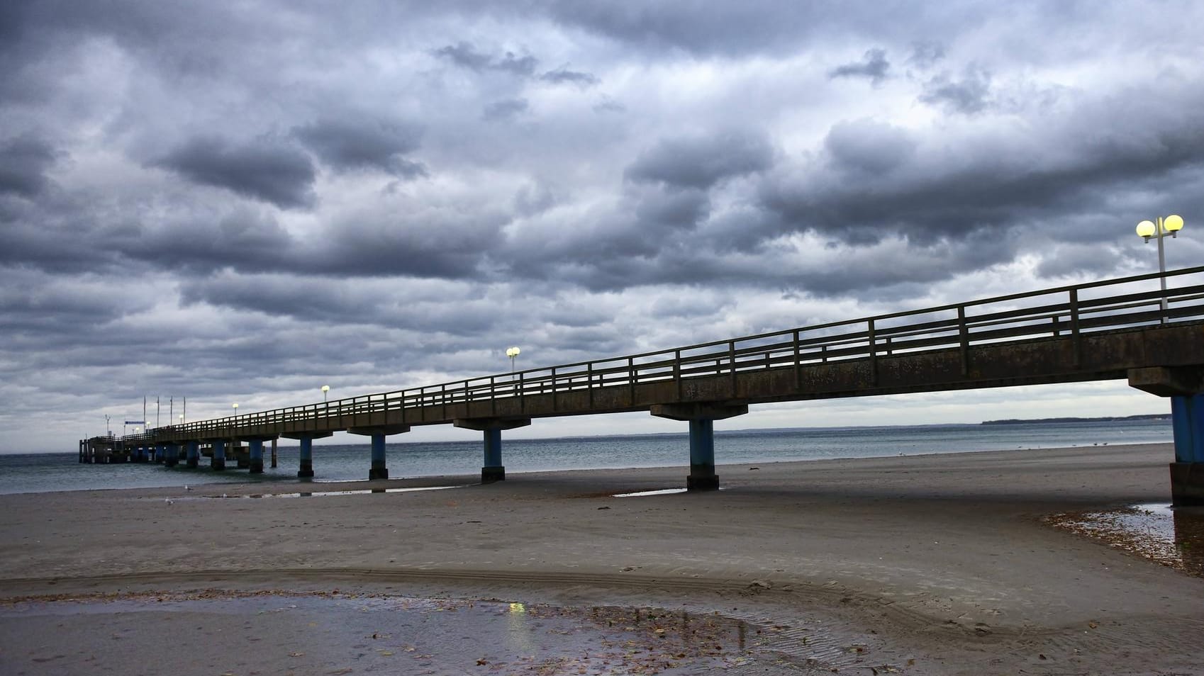 Dunkle Wolken über einer Seebrücke im schleswig-holsteinischen Scharbeutz: Dort trieb der Wind zwei Kinder auf einer Luftmatratze aufs Meer hinaus. (Symbolfoto)