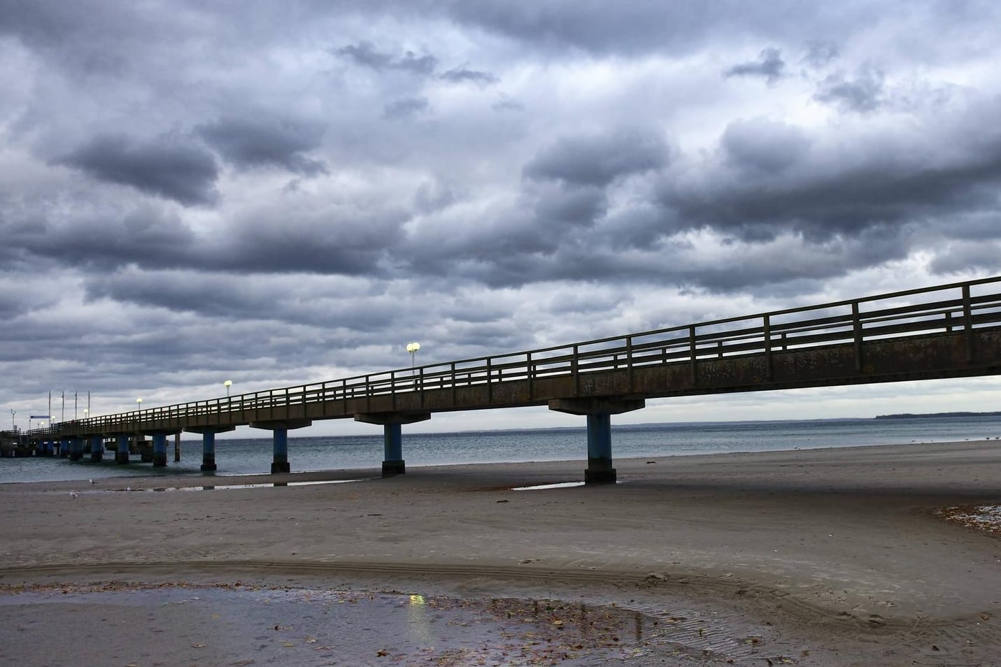 Dunkle Wolken über einer Seebrücke im schleswig-holsteinischen Scharbeutz: Dort trieb der Wind zwei Kinder auf einer Luftmatratze aufs Meer hinaus. (Symbolfoto)