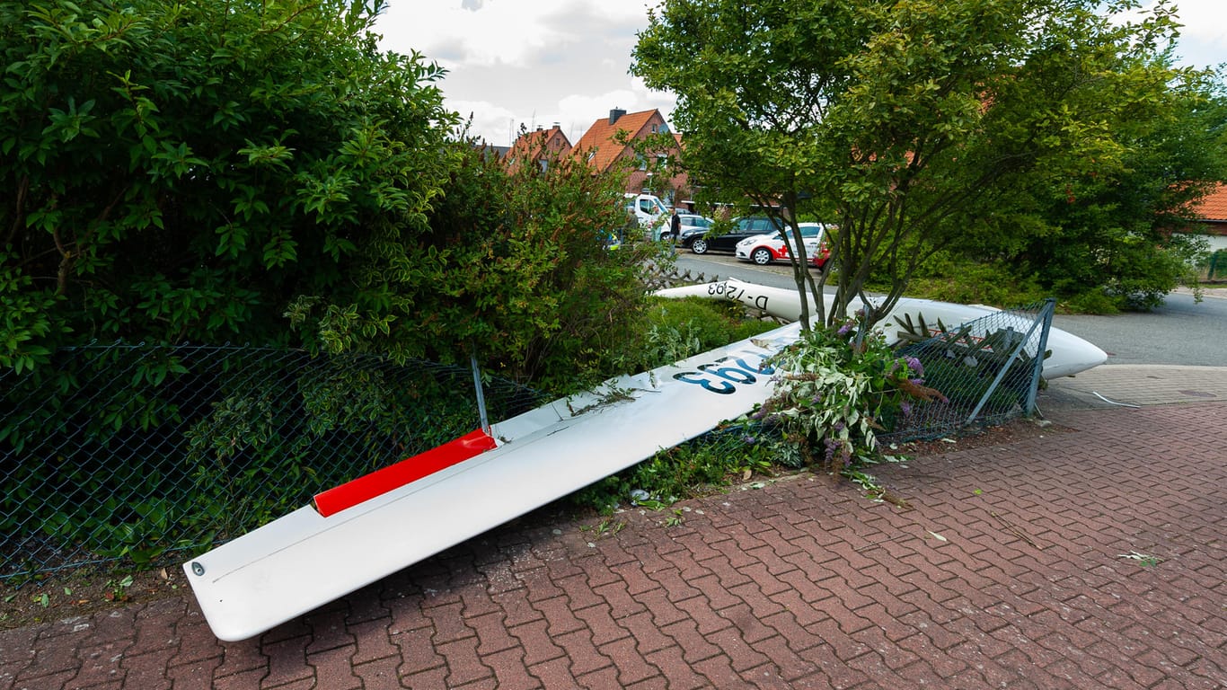 Ein zerstörtes Segelflugzeug liegt nach dem Absturz teils in einem Vorgarten und teils auf der Straße in einem Wohngebiet.