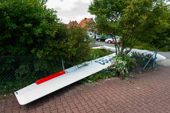 Ein zerstörtes Segelflugzeug liegt nach dem Absturz teils in einem Vorgarten und teils auf der Straße in einem Wohngebiet.