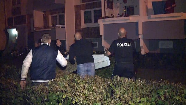 Dramatische Szenen in Rostock: Polizisten und Anwohner stehen vor einem Hochhaus und breiten ein Tuch aus, als ein Mann in einem Obergeschoss einen Säugling über die Balkonbrüstung hält und droht, ihn fallen zu lassen. Dramatische Szenen in Rostock: Polizisten und Anwohner stehen vor einem Hochhaus und breiten ein Tuch aus, als ein Mann in einem Obergeschoss einen Säugling über die Balkonbrüstung hält und droht, ihn fallen zu lassen.