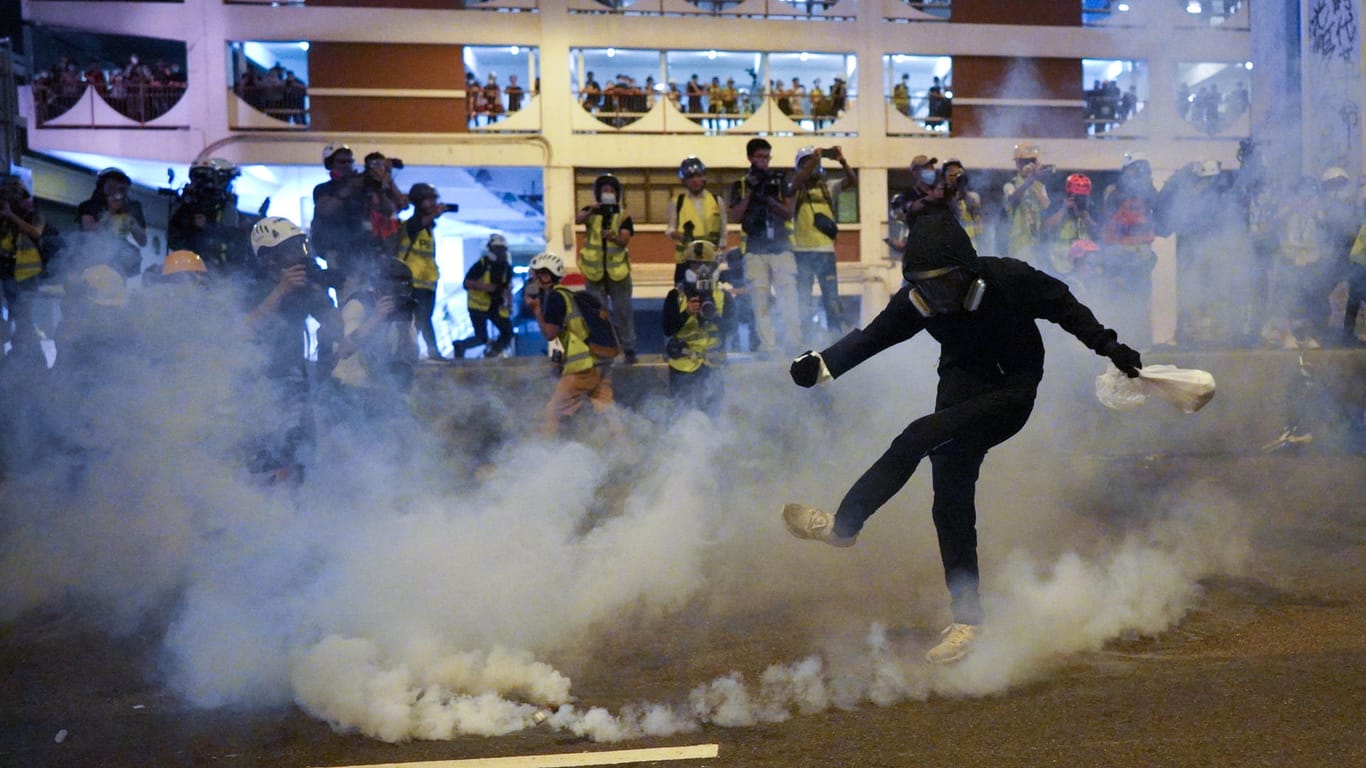 Ein Demonstrant stößt einen Tränengaskanister weg.