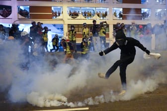 Ein Demonstrant stößt einen Tränengaskanister weg.
