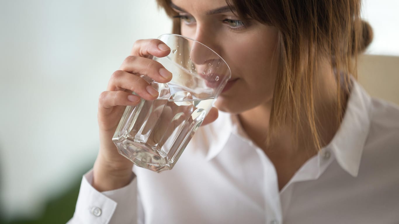 Eine Frau trinkt aus einem Wasserglas: Fast jeder dritten Befragten fällt es laut Studienergebnissen schwer, während der Arbeit genügend zu trinken.