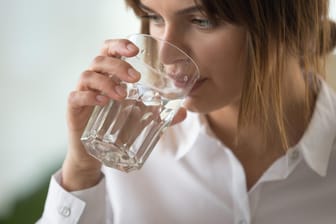 Eine Frau trinkt aus einem Wasserglas: Fast jeder dritten Befragten fällt es laut Studienergebnissen schwer, während der Arbeit genügend zu trinken.