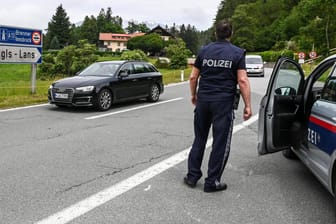 Österreichische Polizisten kontrollieren an einer Autobahnabfahrt deutsche Autofahrer: Im Raum Innsbruck sind Ausweichrouten am Wochenende für Urlauber gesperrt.