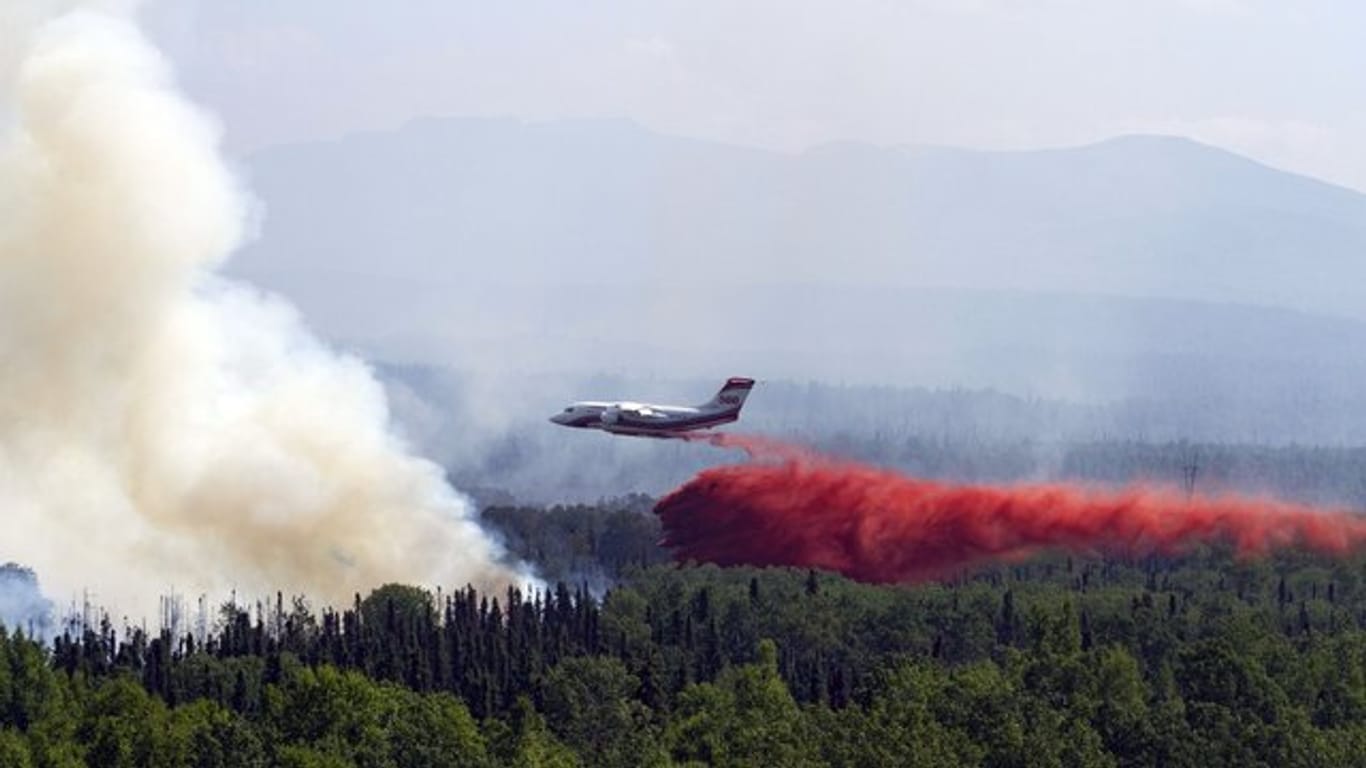 Ein Löschflugzeug lässt über einem in der Nähe von Montana Creek brennenden Wald Löschmittel ab.