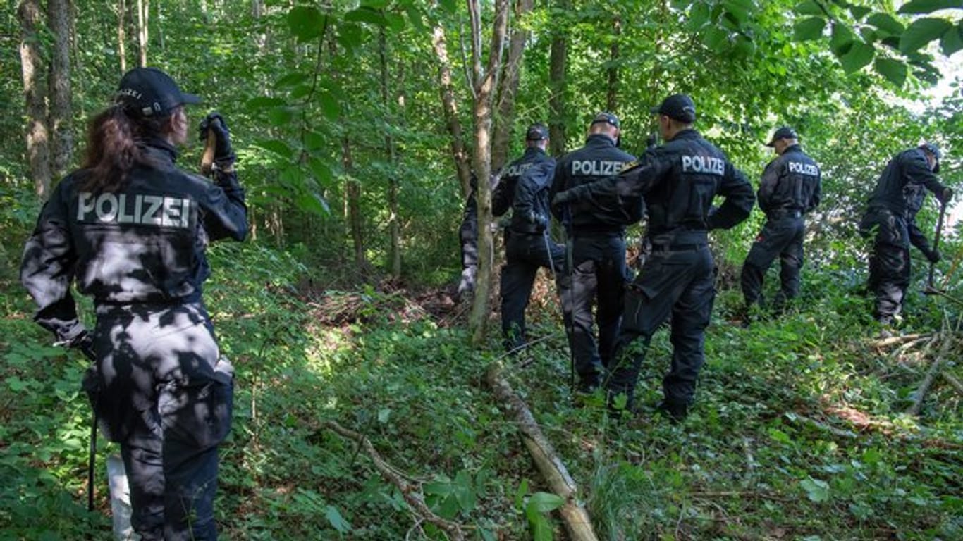 Polizisten suchen in einem Waldstück bei München nach zwei Leichen.