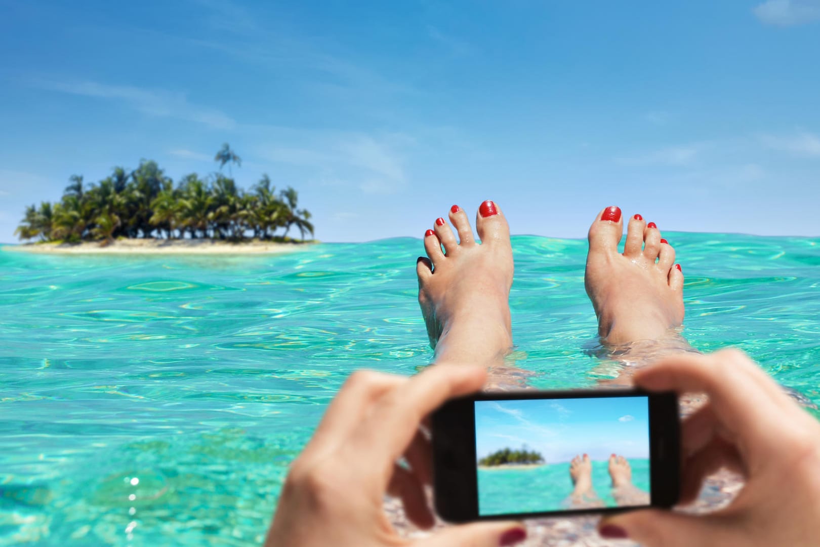Eine Frau macht ein Foto am Strand: Wer Urlaubsbilder postet, macht damit öffentlich, dass seine Wohnung derzeit unbewacht ist.
