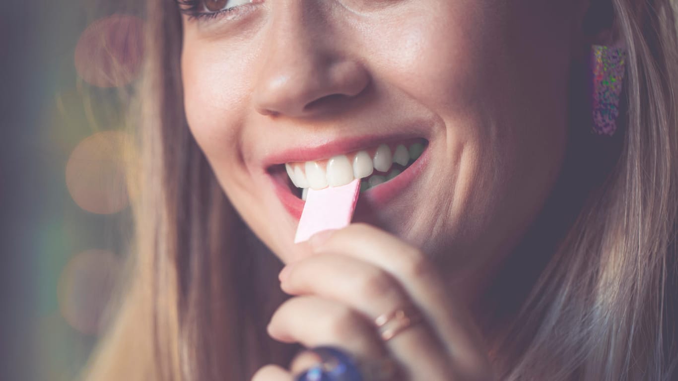 Eine Frau steckt sich einen Kaugummi in den Mund: Kaubewegungen können die Konzentration fördern.