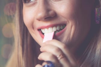 Eine Frau steckt sich einen Kaugummi in den Mund: Kaubewegungen können die Konzentration fördern.