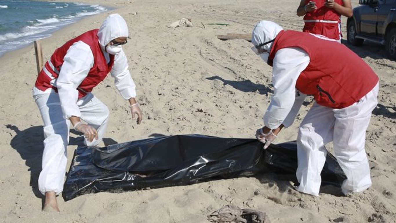 Libysche Mitarbeiter des Roten Halbmonds bergen die Leiche eines ertrunkenen Migranten.