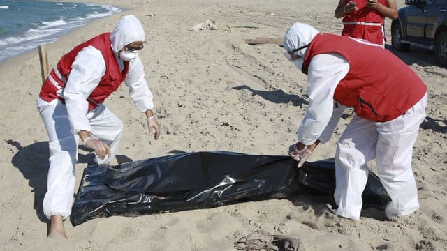 Libysche Mitarbeiter des Roten Halbmonds bergen die Leiche eines ertrunkenen Migranten. Libysche Mitarbeiter des Roten Halbmonds bergen die Leiche eines ertrunkenen Migranten.