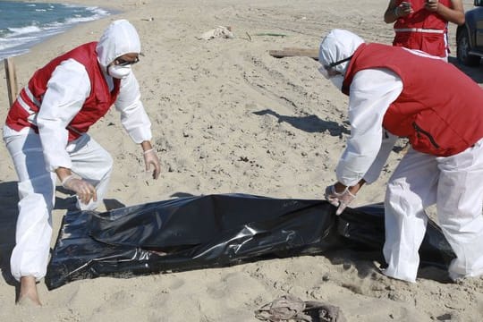 Libysche Mitarbeiter des Roten Halbmonds bergen die Leiche eines ertrunkenen Migranten.