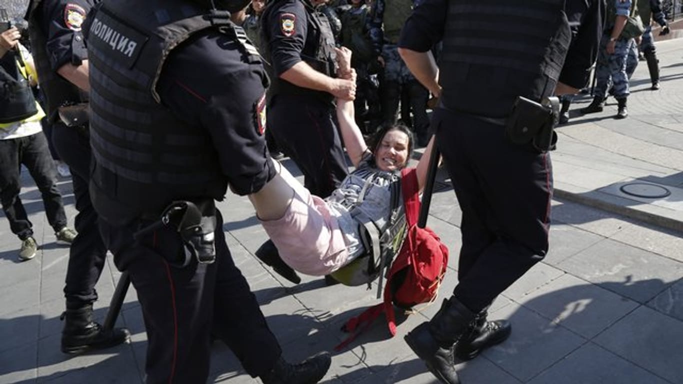 Im Zentrum Moskaus führen Polizisten eine Frau ab.