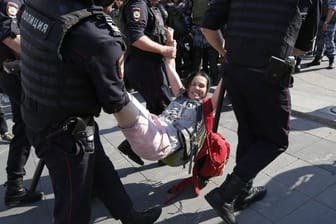 Im Zentrum Moskaus führen Polizisten eine Frau ab.