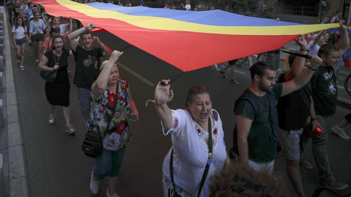 Menschen halten eine rumänische Flagge während einer Demonstration zum Gedenken an ein getötetes 15-jähriges Mädchen in Bukarest.