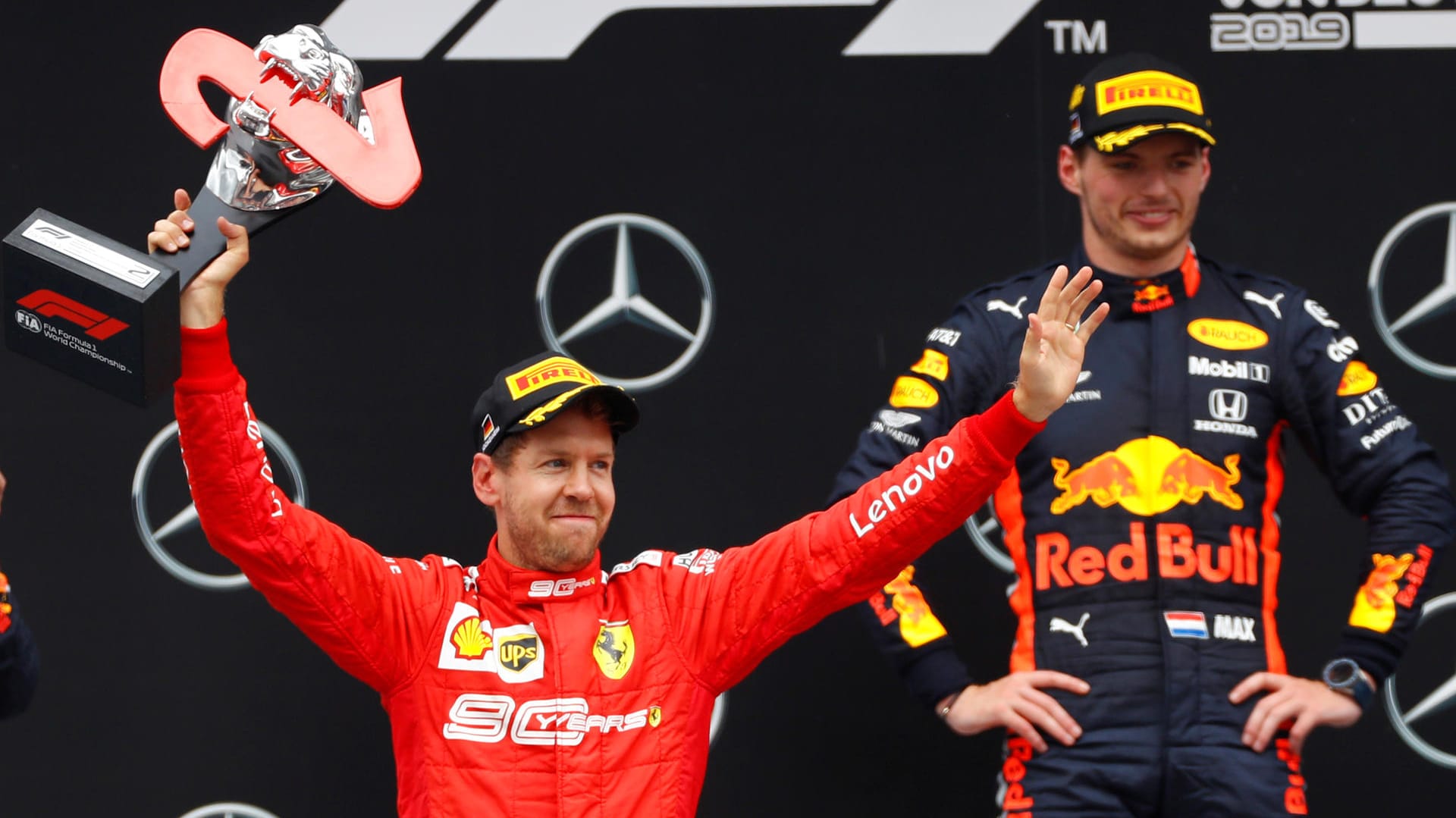 Sebastian Vettel (rot) jubelt auf dem Podium über seinen Platz, im Hintergrund strahlt der Sieger Max Verstappen.