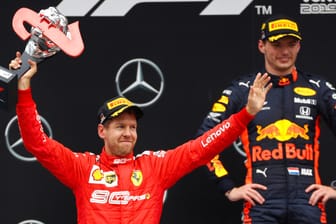 Sebastian Vettel (rot) jubelt auf dem Podium über seinen Platz, im Hintergrund strahlt der Sieger Max Verstappen.