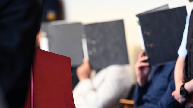 Angeklagte sitzen vor dem Prozessbeginn im Gerichtssaal im Landgericht in Freiburg.